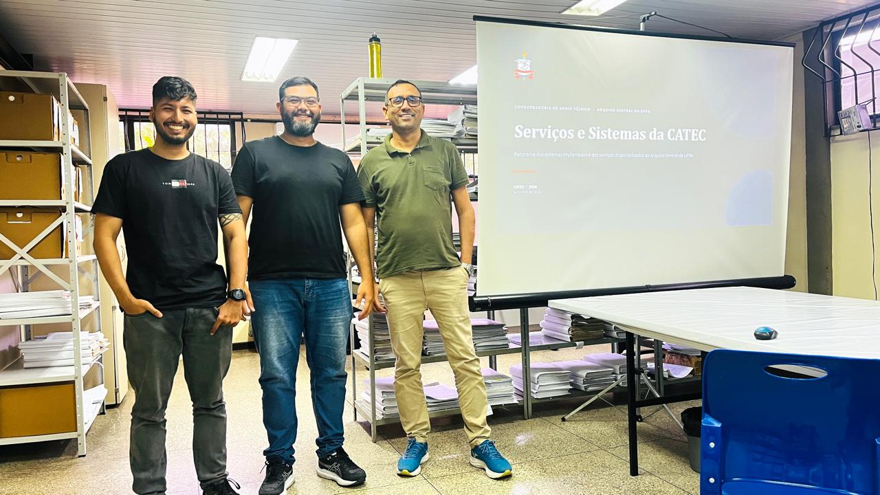 Equipe da CATEC em frente à tela de projeção com o título Serviços e Sistemas da CATEC, no Arquivo Central da UFPA
